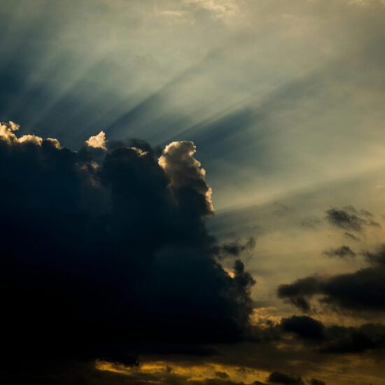 Dark clouds with dramatic sunbeams and a golden twilight sky, creating a sense of hope.