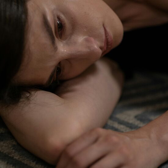Close-up of a woman lying down, expressing sadness and crying.